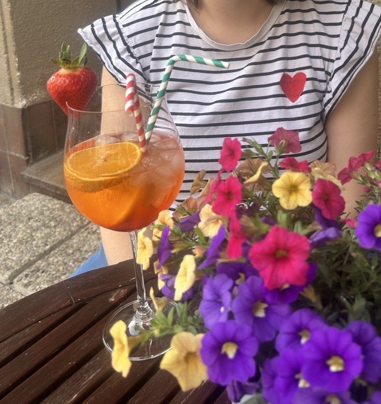 Aperol spritz with strawberry garnish next to summer flowers